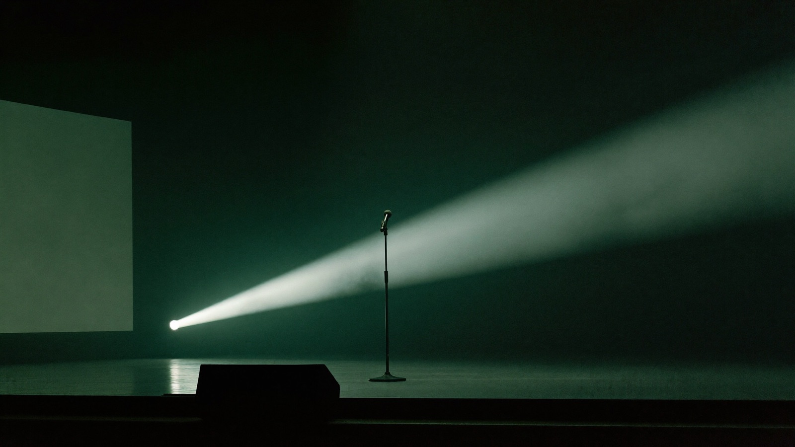 A single cool spotlight on a microphone stand on a dark keynote stage